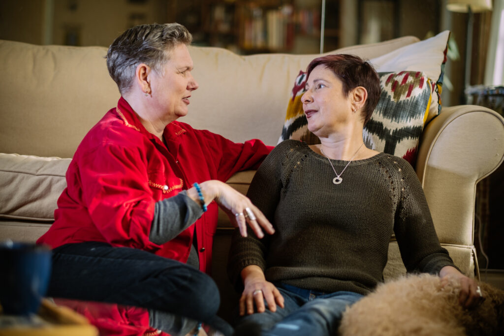 LGBTQ+ couple sitting together and sharing a heartfelt conversation, representing the safe and compassionate space of inclusive couples and relationship therapy
